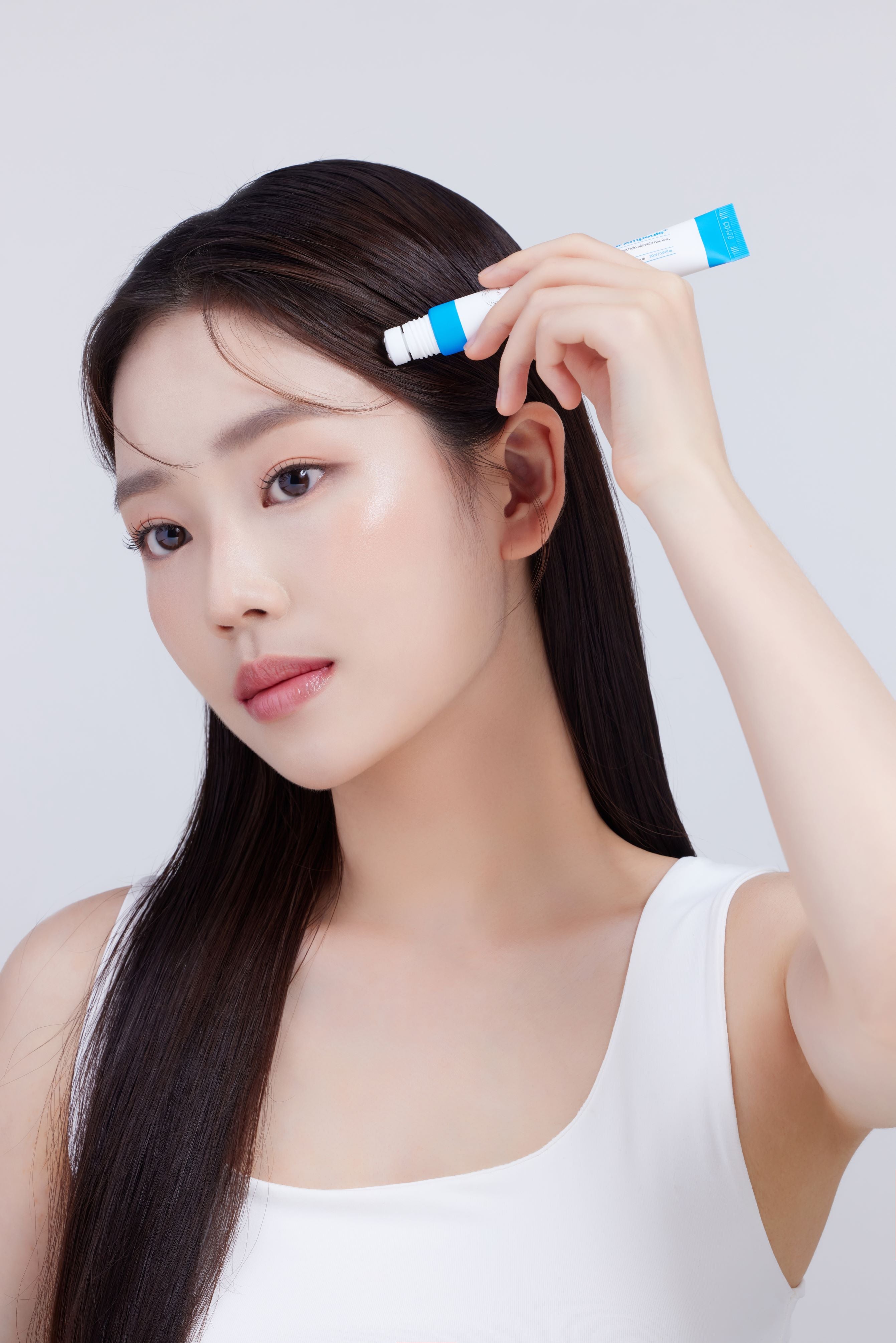 Young woman applying Dr.33 hair ampoule to her hairline, showcasing the product's effectiveness in promoting hair growth and achieving a healthy, glowing look.